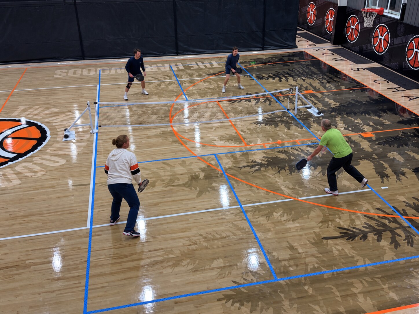 Players competing in a doubles pickleball game at The Hardwoods